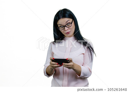 Expressive young asian woman playing video game with her eyes wide open. Isolated on white background. Expressive young asian woman playing video game with her eyes wide open. Isolated on white background. 105261648