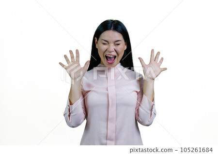 Young brunette asian woman is screaming out loud. Korean girl with her hands up. Isolated on white background. 105261684