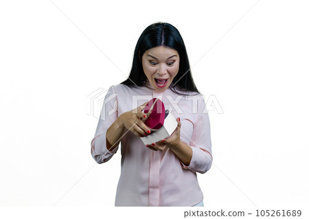 Extremely surprised asian woman is opening a heart-shaped gift box.Valentines day or anniversary. Isolated on white background. 105261689