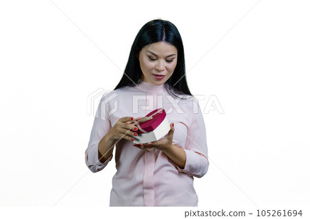 Young asian woman is opening a heart-shaped gift box. Valentines day or anniversary. Isolated on white background. 105261694