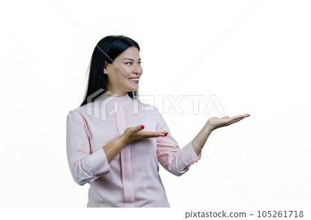 Smiling young cheerful asian woman showing copy space with both hands. Isolated on white background. 105261718