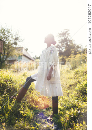 Beautiful young Indian woman smelling flower in the park, wearing white dress Beautiful young Indian woman smelling flower in the park, wearing white dress 105262047