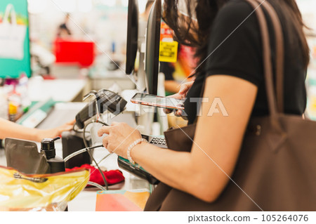 Woman customer scanning QR code payment via mobile phone at cashier counter in store. Woman customer scanning QR code payment via mobile phone at cashier counter in store. 105264076
