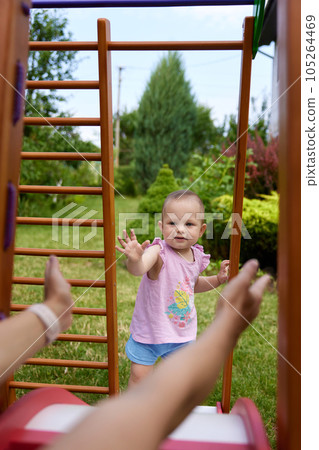 little baby girl with mother on slide in playground 105264469