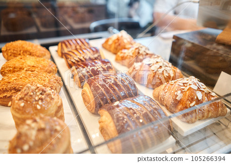 fresh pastries with chocolate. A variety of fresh pastries in the bakery window. almond croissant is fresh and hot in a cafe next to other types of pastries. The interior of an Italian restaurant. 105266394