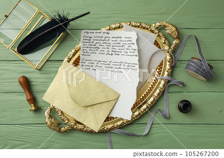 Golden tray with letter, feather and gray ribbon on green wooden background, top view Golden tray with letter, feather and gray ribbon on green wooden background, top view 105267200