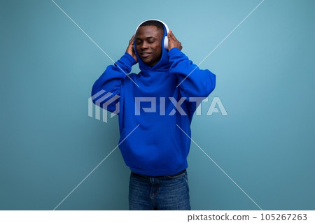 handsome energetic young american male dj listening to music with headphones on background with copy handsome energetic young american male dj listening to music with headphones on background with copy 105267263