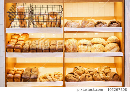 Different kinds of bread on the counter in the bakery shop. Fresh bread counter. Modern bakery with different kinds of bread, cakes and buns  105267808