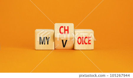My voice and choice symbol. Businessman turns wooden cubes and changes the concept word my choice to voice. Beautiful orange table orange background, copy space. Business and my voice choice concept. 105267944