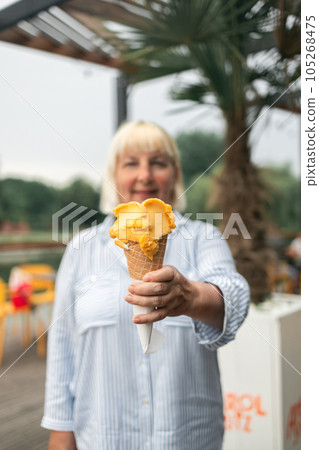 Happy smiling senior woman dressed in stylish clothes eating ice cream in the city outdoors cafe interior Happy smiling senior woman dressed in stylish clothes eating ice cream in the city outdoors cafe interior 105268475