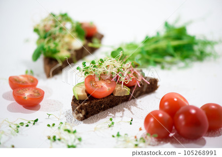 Toasts with microgreens. Hand holds a healthy toast. Healthy food concept. Super food. Toasts with microgreens. Hand holds a healthy toast. Healthy food concept. Super food. 105268991