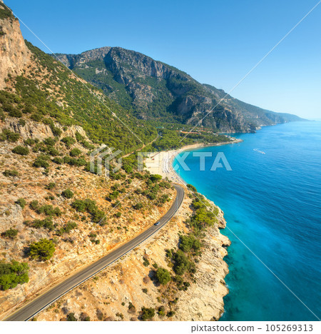 Aerial view of mountain road near blue sea, sandy beach at sunset 105269313