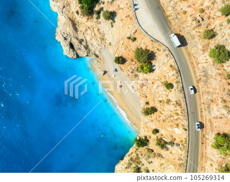 Aerial view of mountain road near blue sea, sandy beach at sunset 105269314