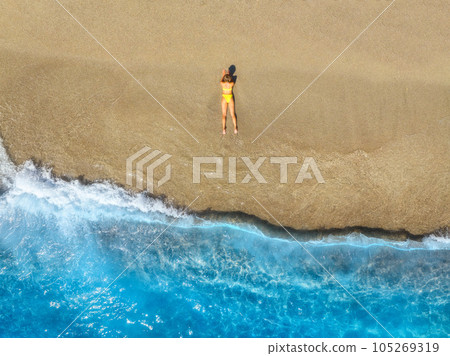 Aerial view of woman on the empty sandy beach near sea with wave Aerial view of woman on the empty sandy beach near sea with wave 105269319