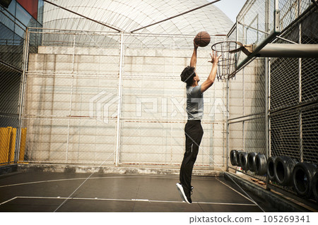 young asian adult man basketball player attempting a dunk on outdoor court young asian adult man basketball player attempting a dunk on outdoor court 105269341