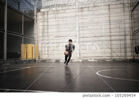 young asian man basketball player attempting a dunk on outdoor court 105269454