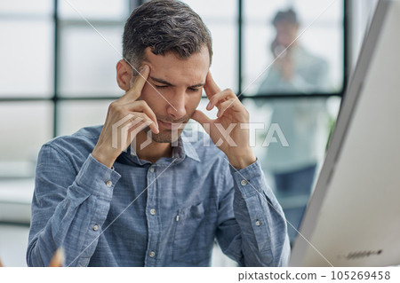 Businessman trying to concentrate and massaging his whiskey while sitting at the table 105269458