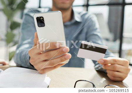 Close up millennial man holding smartphone and banking credit card Close up millennial man holding smartphone and banking credit card 105269515