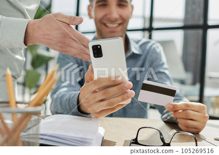 a man holds a smartphone and a bank credit card, participates in mobile online shopping 105269516