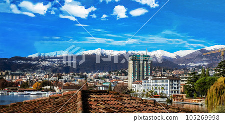 Day winter view on Lugano and snow-capped mountains behind and forest behind Day winter view on Lugano and snow-capped mountains behind and forest behind 105269998