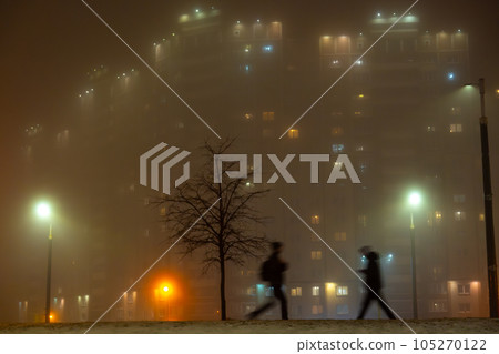 Misty street at night with people walking 105270122