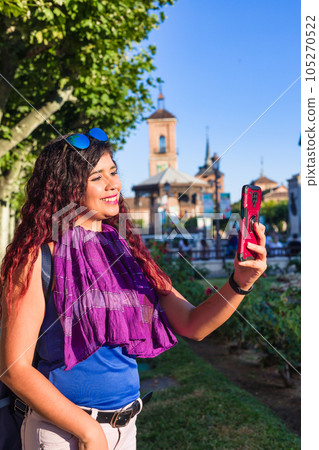 Alcala de Henares. Latin mid-woman travel holiday lifestyle portrait happy with smartphone in Spain 105270522