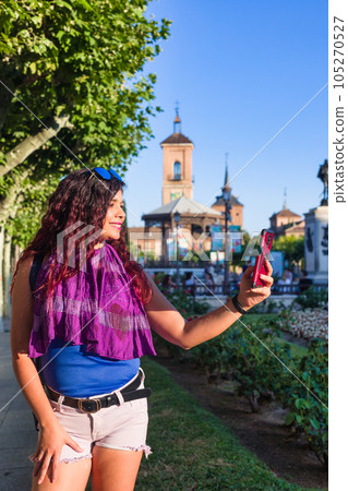 Alcala de Henares. Latin mid-woman travel holiday lifestyle portrait happy with smartphone in Spain 105270527