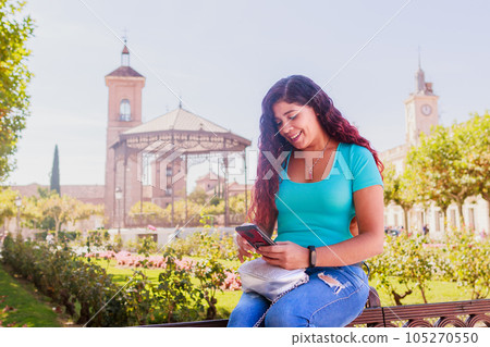 Alcala de Henares. Latin mid-woman travel holiday lifestyle portrait happy with smartphone in Spain 105270550