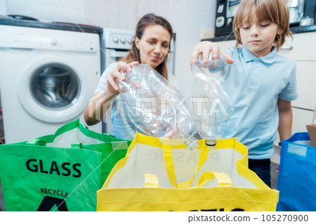 Selective focus on plastic bottles, concept of recycling. Mother educates son on how sort garbage into different bins on kitchen. Family sorting garbage at home. aware environmental importance Selective focus on plastic bottles, concept of recycling. Mother educates son on how sort garbage into different bins on kitchen. Family sorting garbage at home. aware environmental importance 105270900
