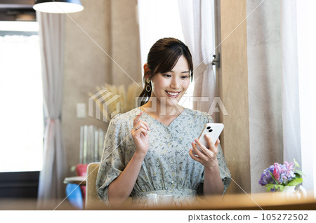 A woman using her smartphone in a cafe A woman using her smartphone in a cafe 105272502