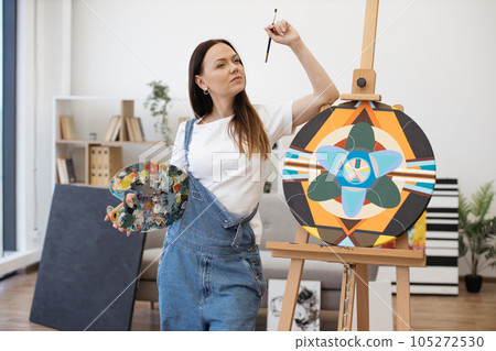 Pensive lady leaning on easel and thinking on new ideas Pensive lady leaning on easel and thinking on new ideas 105272530