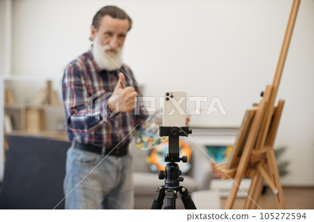 Man on retirement recording video on smartphone at studio 105272594