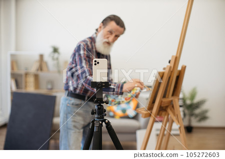 Senior painter making video recording on white smartphone Senior painter making video recording on white smartphone 105272603