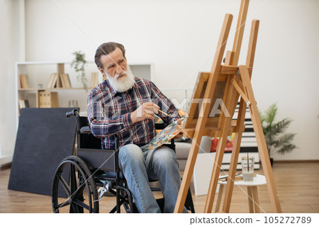 Older painter with disability working on art project indoors Older painter with disability working on art project indoors 105272789