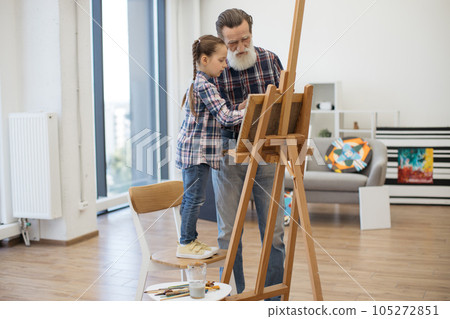 Child enjoying art making with grandpa in home studio 105272851