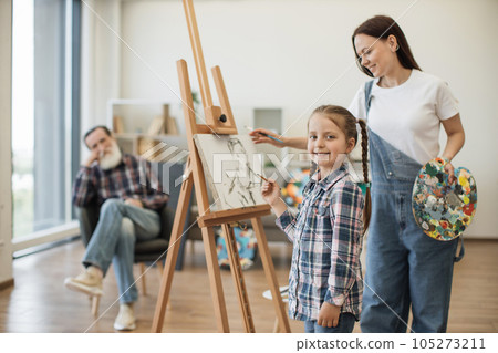 Girl spending time with mom and grandpa in art studio 105273211