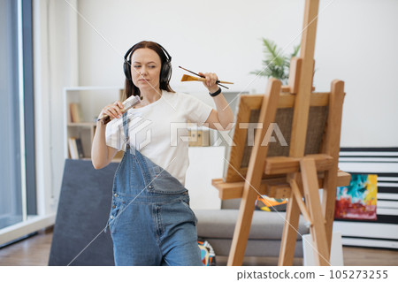 Lady with brush moving to beat of song via headphones 105273255