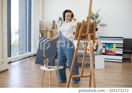 Artist handling brush to tunes in hands-free device indoors 105273272