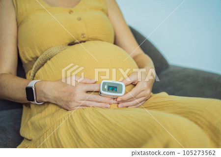 Pregnant woman with pulse oximeter on finger. Doctor measuring oxygen saturation level while visiting expectant mother with coronavirus disease at home, cropped. Pregnancy and covid-19 concept Pregnant woman with pulse oximeter on finger. Doctor measuring oxygen saturation level while visiting expectant mother with coronavirus disease at home, cropped. Pregnancy and covid-19 concept 105273562