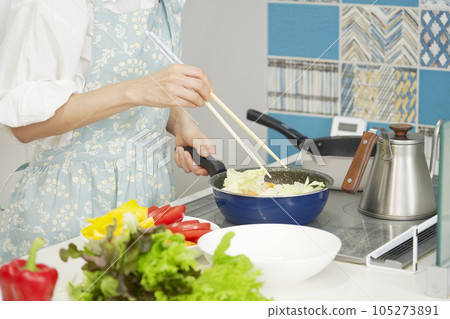 Woman stir-frying vegetables at home faceless 105273891