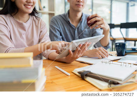 Two Asian students learning together with a laptop and tutor together at cafe 105274727