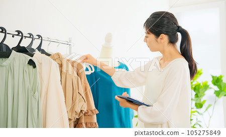 Apparel clerk checking products while looking at a tablet Apparel clerk checking products while looking at a tablet 105275849