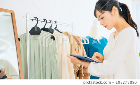 服裝店員一邊看平板電腦一邊檢查產品 105275850