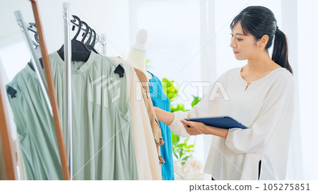 Apparel clerk checking products while looking at a tablet Apparel clerk checking products while looking at a tablet 105275851