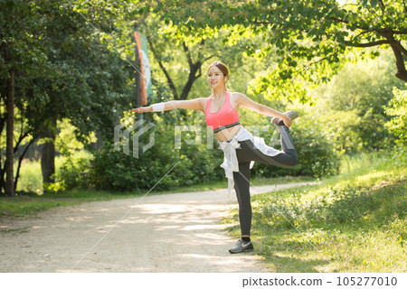 a beautiful young woman exercising in the park on a summer morning 105277010