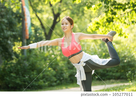 a beautiful young woman exercising in the park on a summer morning 105277011