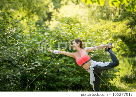 a beautiful young woman exercising in the park on a summer morning 105277012