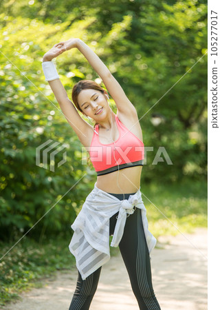 a beautiful young woman exercising in the park on a summer morning 105277017