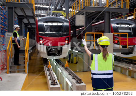 Young caucasian engineer woman or worker signal while engineer man checking electric train. Young caucasian engineer woman or worker signal while engineer man checking electric train. 105278292