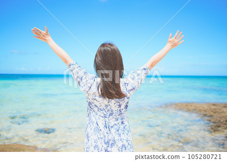 Back view of a woman feeling the waves on the beach in Okinawa Back view of a woman feeling the waves on the beach in Okinawa 105280721